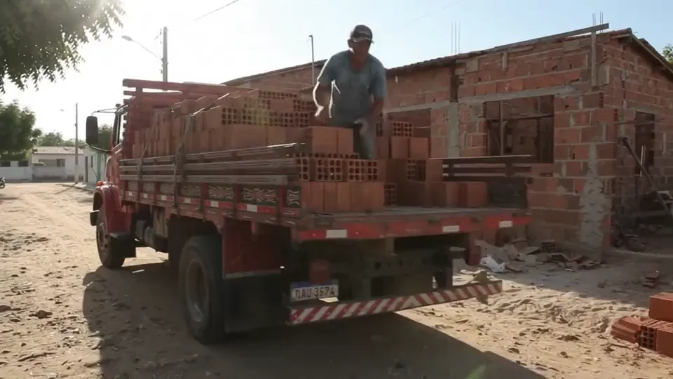 Caminhão de tijolos sendo descarregado na frente de uma casa em construção